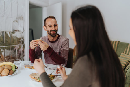 Smiling man sharing a meal with a friend at homeの写真素材