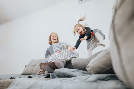 Two joyful children playing together at home on a comfortable sofaの写真素材