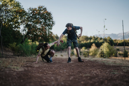 Two hikers help each other on a rural dirt road during a sunny outdoor trekの写真素材
