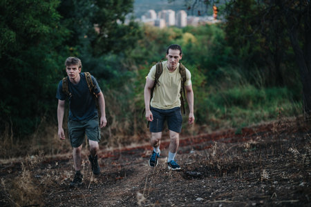 Two hikers on a dirt trail with backpacks trekking through nature, city skyline in the distance