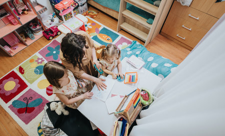 Mother and daughters engaged in creative activities in a cozy playroomの写真素材