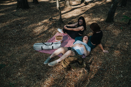 Friends enjoy a relaxing day in the forest on a picnic blanketの写真素材