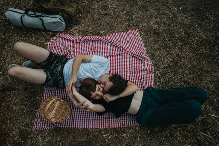 Couple lying together on a picnic blanket outdoors, embracing and relaxingの写真素材