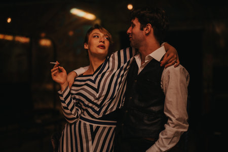 Night out couple embraces in a dimly lit urban setting with stylish attireの写真素材