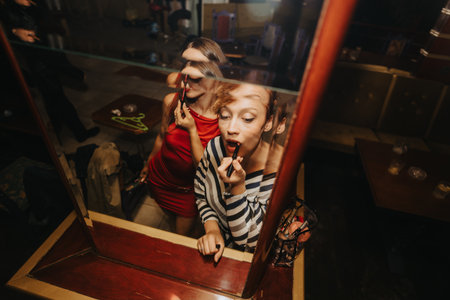 Friends apply lipstick in a dressing room before a stylish night out togetherの写真素材