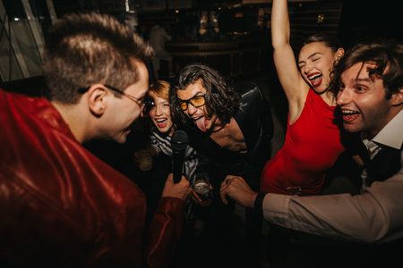 Friends sing and dance at a lively night out party, smiling, celebrating togetherの写真素材