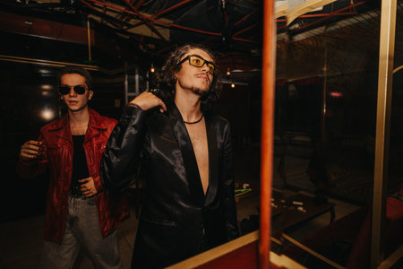 Friends at a nightclub, stylish men wearing sunglasses, leather jacket and sleek suit, nightlife fashionの写真素材