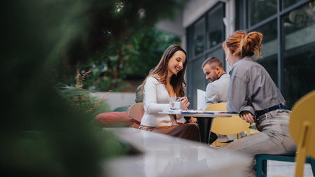 Friends at an outdoor cafe share a relaxed business meeting with smiles and conversationの写真素材