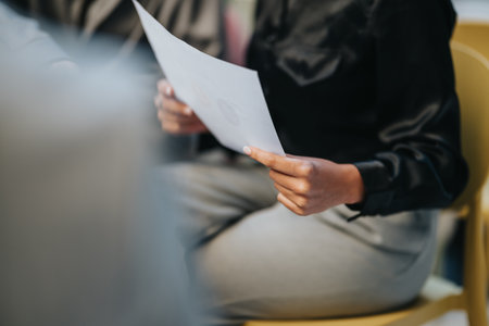 People in a meeting hold a document, focusing on discussion and collaboration in a professional settingの写真素材