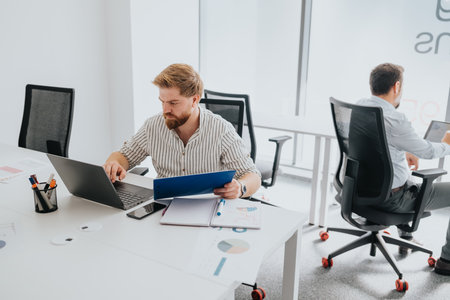Focused professional at a modern office desk with laptop, tablet, and documents in a bright...