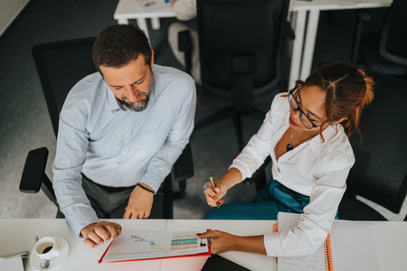 Busy professionals review charts and notes at a bright office desk during a collaborative meetingの写真素材