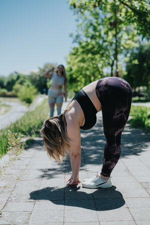 Two women enjoying outdoor exercises and stretching in a sunny park setting