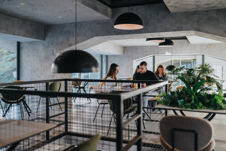 Business colleagues discuss ideas over coffee in a modern coworking cafe settingの写真素材