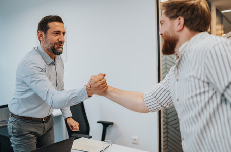 Two colleagues shake hands in a modern office after a successful business meeting agreementの写真素材