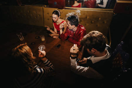 Friends enjoy a night out at a bar, playing cards and chatting over drinks