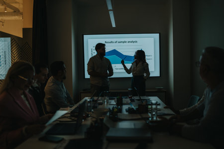 Business meeting presentation in a dim conference room with analysts and a data chart projectionの写真素材