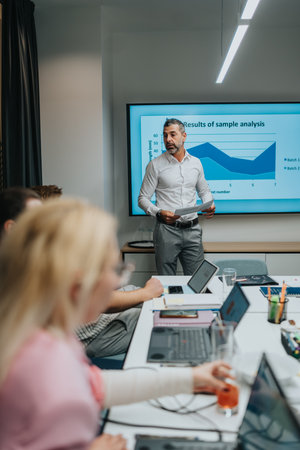 Business presentation in a conference room with a presenter and team analyzing data on a large...
