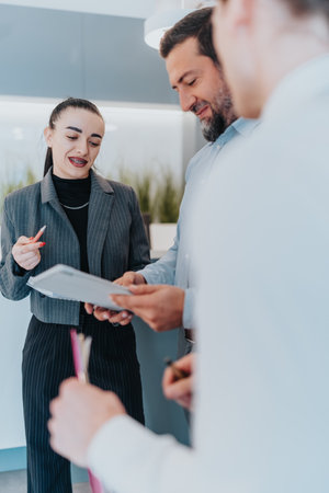 Multicultural business team reviews documents and discusses project in a modern officeの写真素材