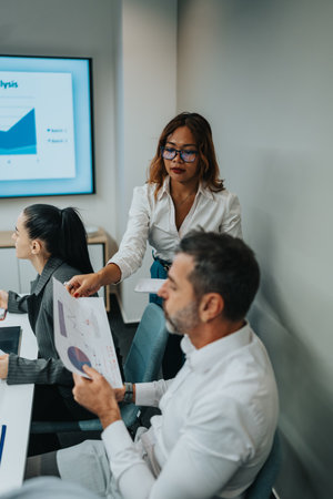 Team meeting in an office as a colleague presents charts to colleagues during a presentationの写真素材