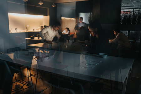 Evening office team meeting in a modern coworking space with glass reflections and warm lightingの写真素材