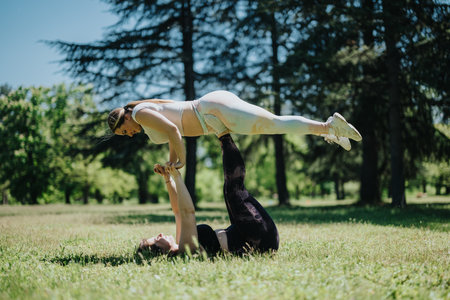 Two women practicing partner acrobatics on a sunny day outdoors