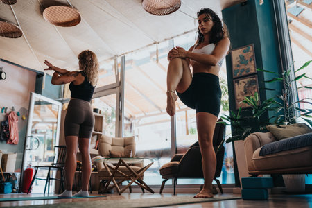 Two women practice yoga in a cozy studio, balancing poses during a serene fitness sessionの写真素材