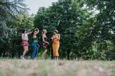 Friends in a park dance together, enjoying a sunny summer day in casual outfitsの写真素材