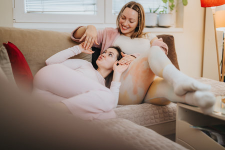 Two women enjoying time together relaxing comfortably at homeの写真素材