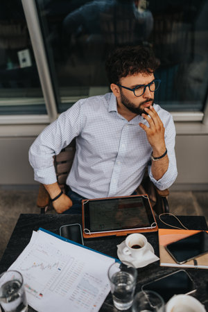 Businessman strategizing while analyzing charts on tablet at an outdoor setting