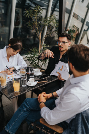 Team discussing business strategies during a casual outdoor meeting at a cafeの写真素材