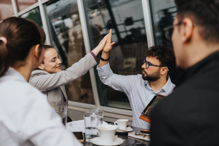 Business colleagues high-fiving while collaborating on a project in a casual settingの写真素材