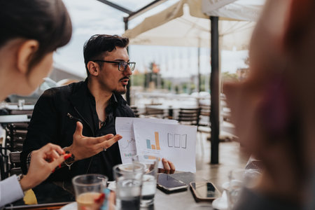 Business group analyzing data charts together during an engaging outdoor meetingの写真素材