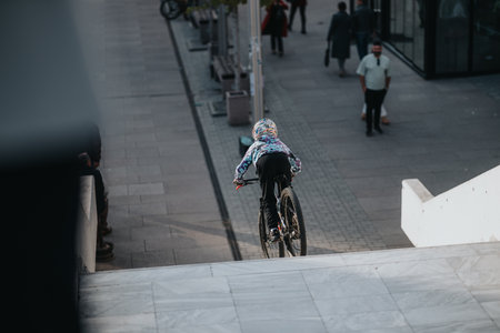 Child riding a bicycle in an urban street scene with colorful helmet outdoorsの写真素材
