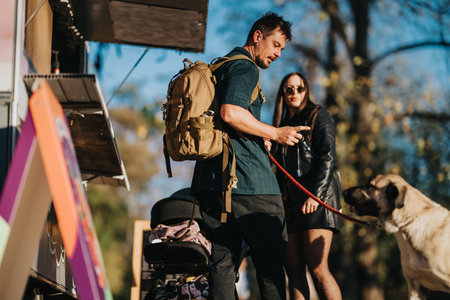 Man with backpack and woman with dog enjoy sunny autumn day in park