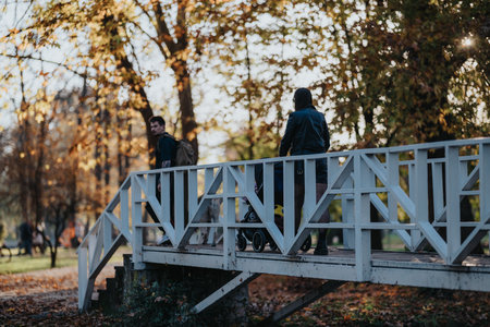 Family on a white wooden bridge in an autumn park, strolling with a strollerの写真素材
