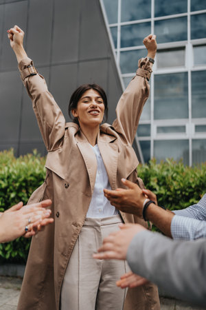 Businesswoman celebrating success during a team gathering outdoorsの写真素材