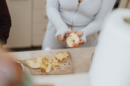 Person peeling and slicing an apple on a cutting board in kitchen