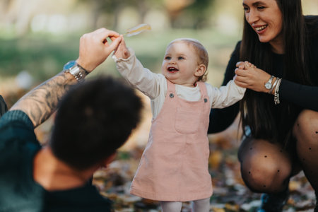 Happy baby and loving family in autumn park enjoying playful moment outdoors