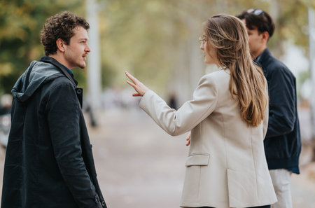 Outdoor conversation between colleagues as a woman in a beige blazer talks with a manの写真素材