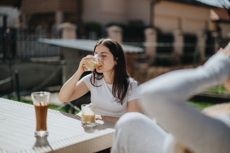 Young woman enjoying a chilled coffee outdoors on a sunny dayの写真素材