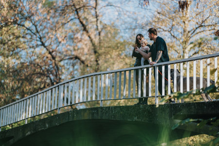 Family on a sunny autumn day walking a bridge with a dog and babyの写真素材
