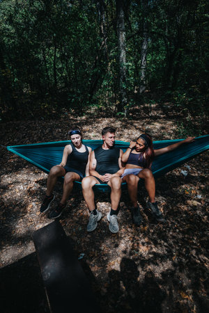 Friends relax in a hammock outdoors in the forest during a casual outdoor breakの写真素材