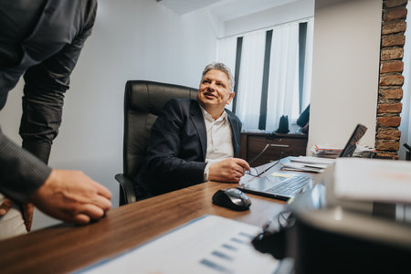 Businessman discussing project ideas with colleague in modern office settingの写真素材