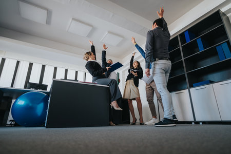 Excited business team celebrating success in a modern office environmentの写真素材