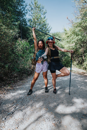 Friends hiking on a forest trail cheerfully posing with hiking poles and backpack gearの写真素材