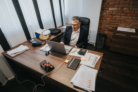Professional office environment featuring a businessman working diligently on his laptopの写真素材