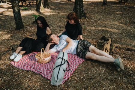 Friends enjoying a relaxed forest picnic together during a sunny day off in natureの写真素材