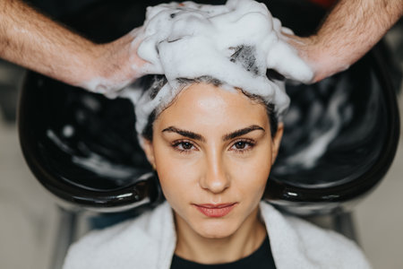 Woman enjoys a professional hair wash at the salon with foamy shampooの写真素材