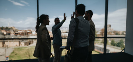 Group of colleagues celebrating in a bright office with a city view and high five gestureの写真素材