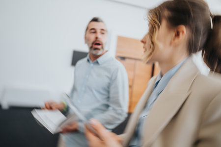 Busy office scene with colleagues in discussion and documents in motion during a workplace meetingの写真素材